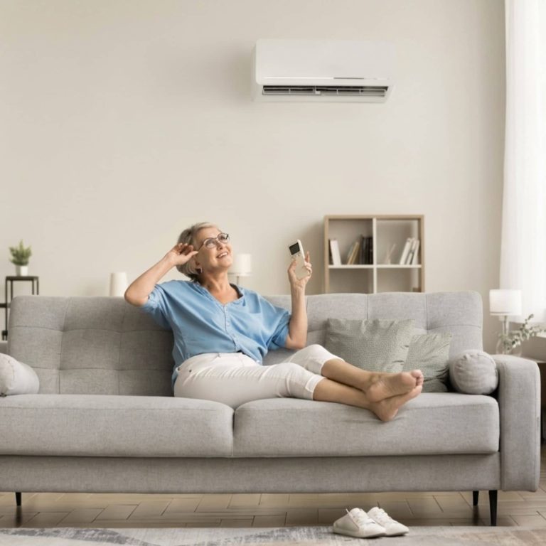 Seniorka ovládá klimatizaci na gauči
